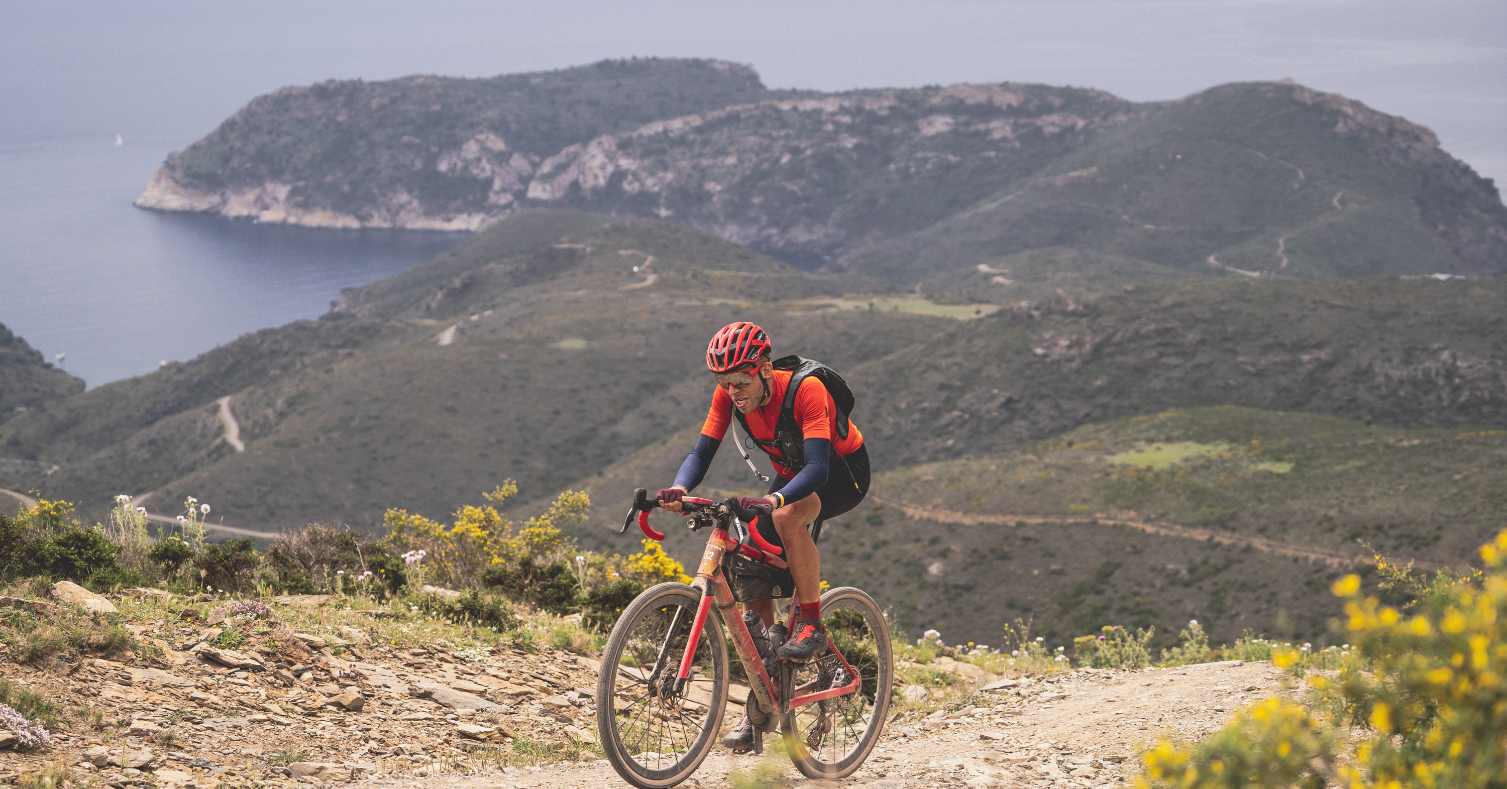 Gravel rider on the Traka route with Costa Brava coastline behind